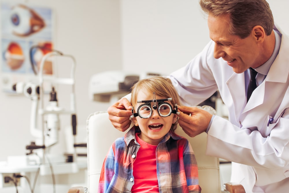 Handsome,Middle,Aged,Ophthalmologist,Examining,Little,Boy,With,Modern,Equipment,