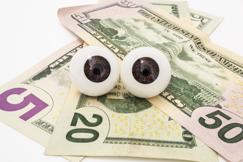 Eye care billing concept with US dollar bills and model eyes