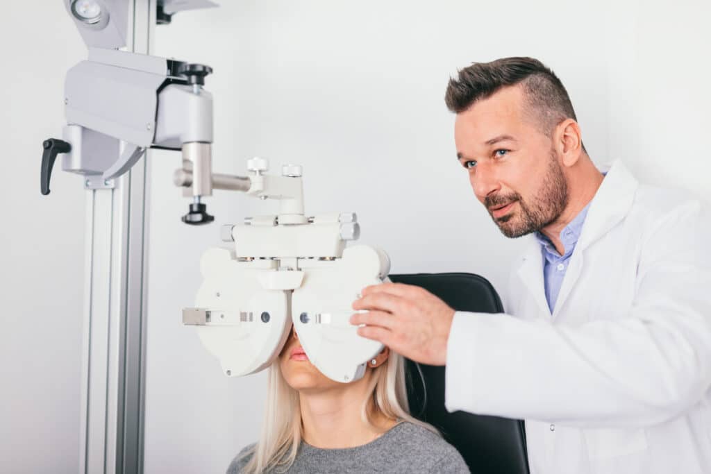 Optometrist adjusting a phoropter during a comprehensive vision examination